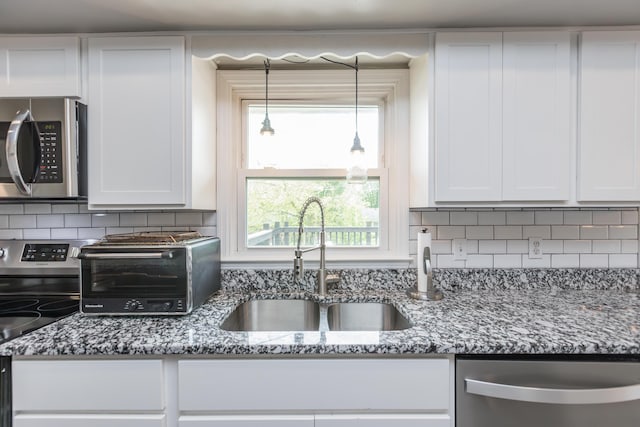 kitchen with white cabinets, stainless steel appliances, a sink, and a toaster