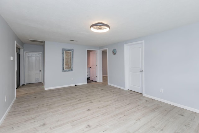 spare room featuring visible vents, baseboards, and light wood-style floors