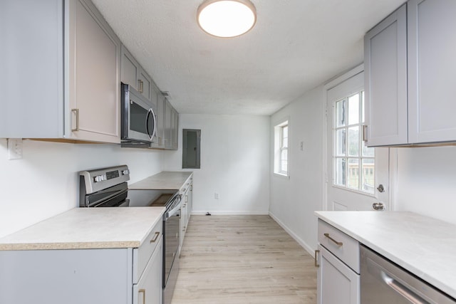kitchen with stainless steel appliances, light countertops, light wood-style floors, gray cabinetry, and a textured ceiling