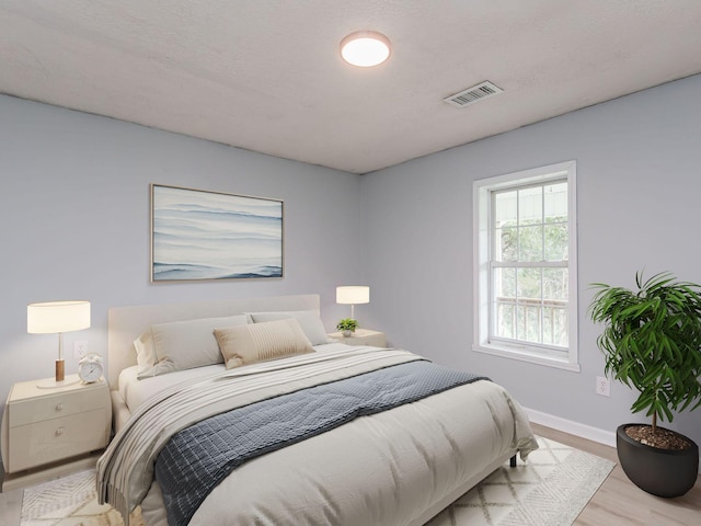 bedroom with wood finished floors, visible vents, and baseboards