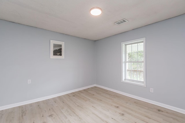 empty room featuring visible vents, baseboards, and wood finished floors