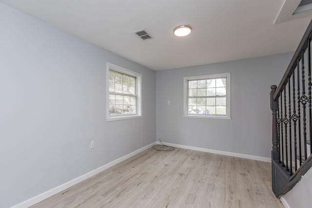 unfurnished room featuring baseboards, visible vents, light wood-style floors, and stairway