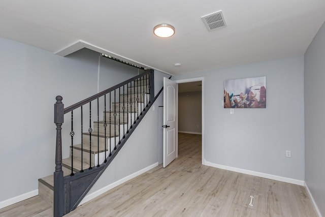 stairs with baseboards, wood finished floors, and visible vents