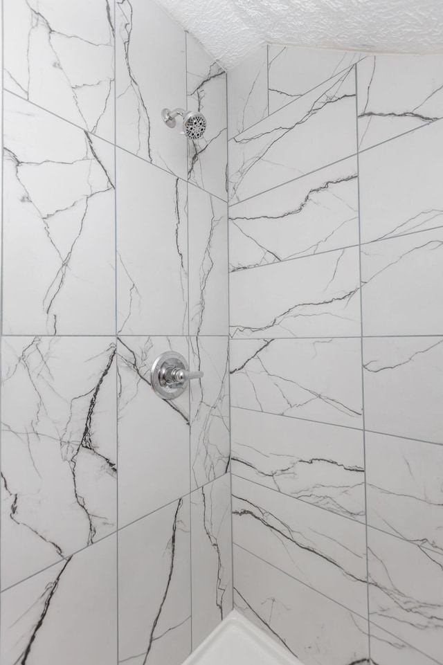 full bath featuring a textured ceiling and tiled shower
