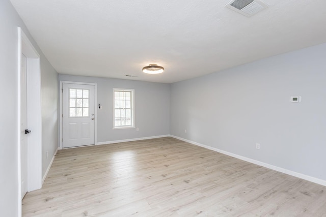 empty room with baseboards, light wood finished floors, and visible vents