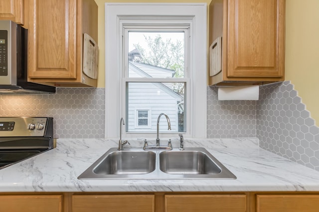 kitchen with stainless steel microwave, backsplash, light stone counters, and a sink