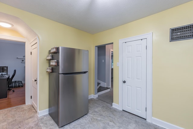 kitchen featuring baseboards, visible vents, and freestanding refrigerator