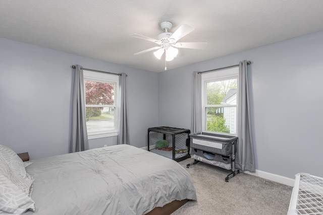 bedroom with multiple windows, ceiling fan, light colored carpet, and baseboards