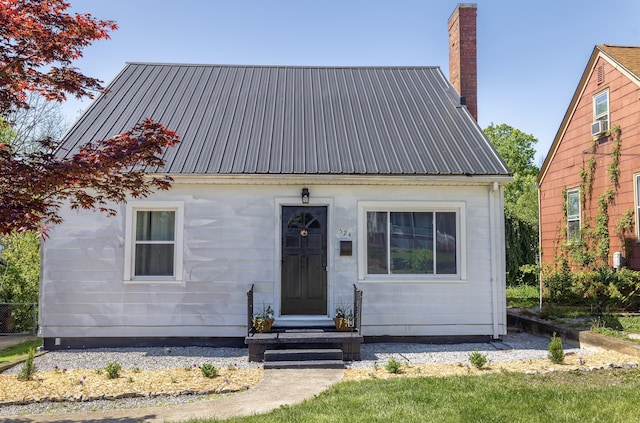 view of front of home featuring metal roof, cooling unit, and a chimney