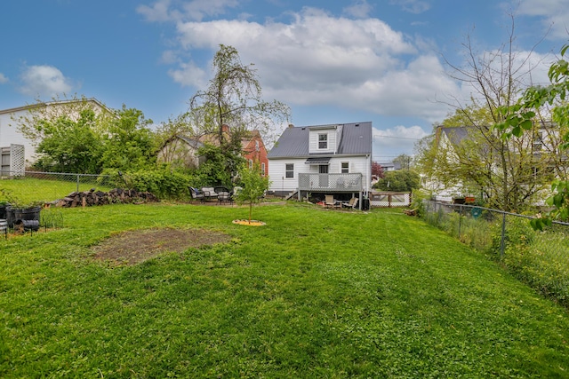rear view of house with a fenced backyard, a yard, and metal roof