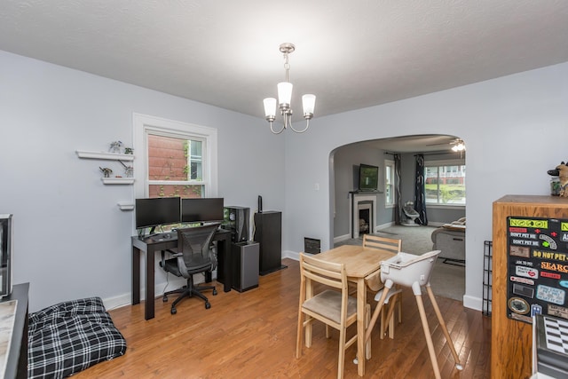 dining space featuring arched walkways, wood finished floors, a chandelier, baseboards, and visible vents