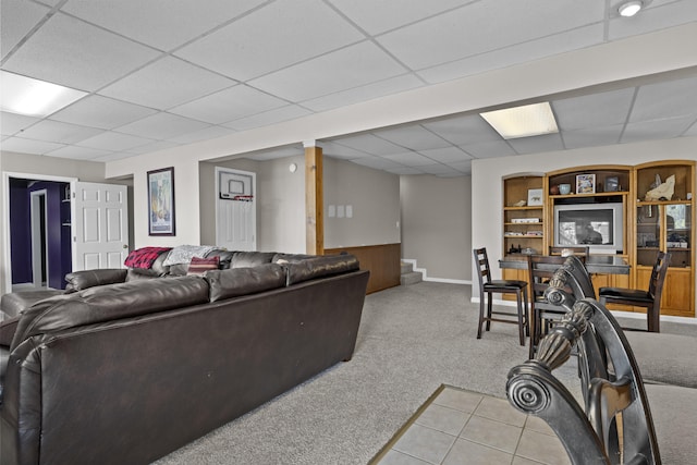 living room featuring a wainscoted wall, a drop ceiling, and light colored carpet