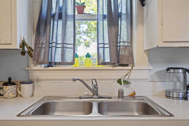 interior details featuring light countertops, white cabinets, and a sink