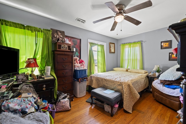 bedroom featuring a ceiling fan, wood finished floors, and visible vents