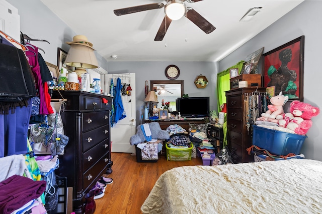 bedroom with a ceiling fan, visible vents, and wood finished floors
