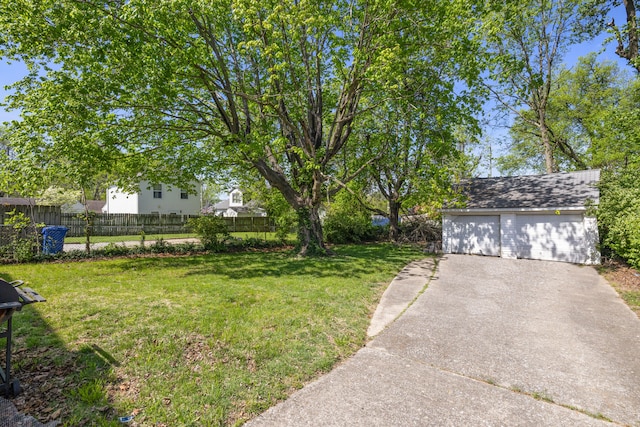 view of yard with a detached garage, fence, and an outdoor structure