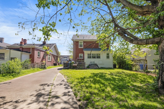 rear view of house with a lawn, fence, and a residential view