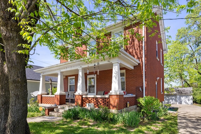 view of front of home with an outdoor structure, a chimney, a porch, and brick siding