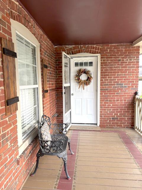 entrance to property with covered porch and brick siding
