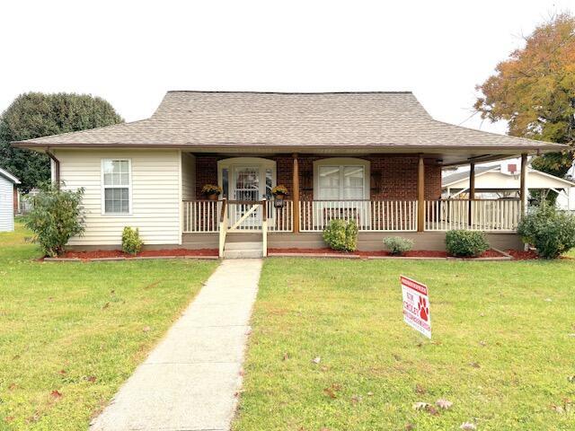 view of front facade featuring a porch, a shingled roof, and a front lawn