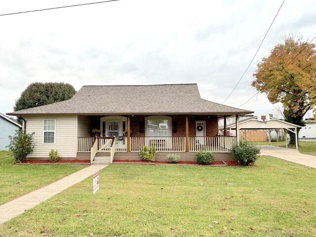 view of front of home featuring driveway, a porch, a front yard, and a carport