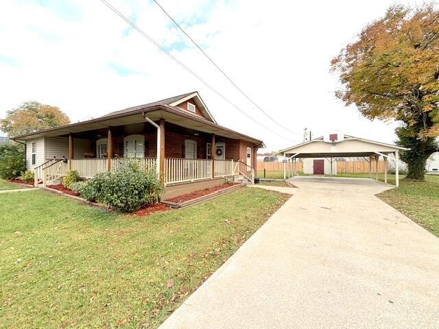 view of front of home featuring a detached carport, driveway, a front lawn, and covered porch