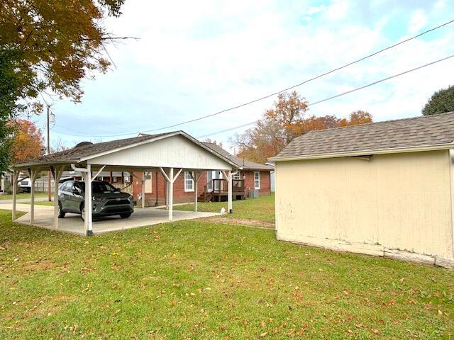 rear view of property featuring a lawn and a carport