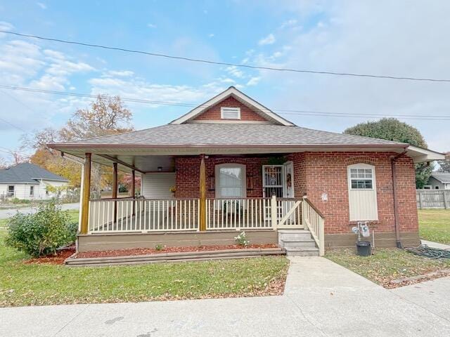 view of front of property with brick siding, roof with shingles, and covered porch