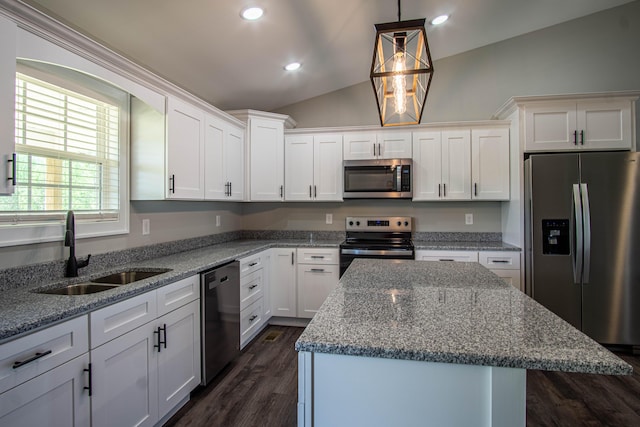 kitchen featuring appliances with stainless steel finishes, vaulted ceiling, white cabinets, a sink, and a center island