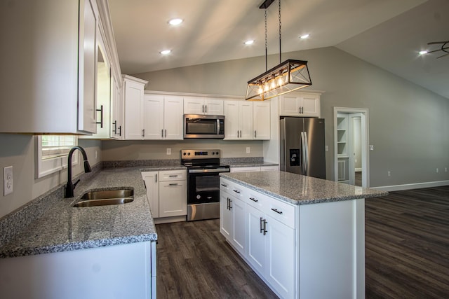 kitchen with dark wood finished floors, appliances with stainless steel finishes, a sink, white cabinetry, and stone countertops