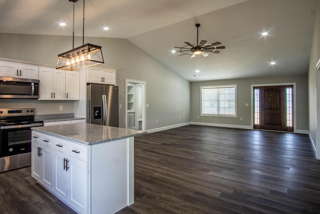 kitchen featuring light stone countertops, stainless steel appliances, white cabinetry, a kitchen island, and open floor plan