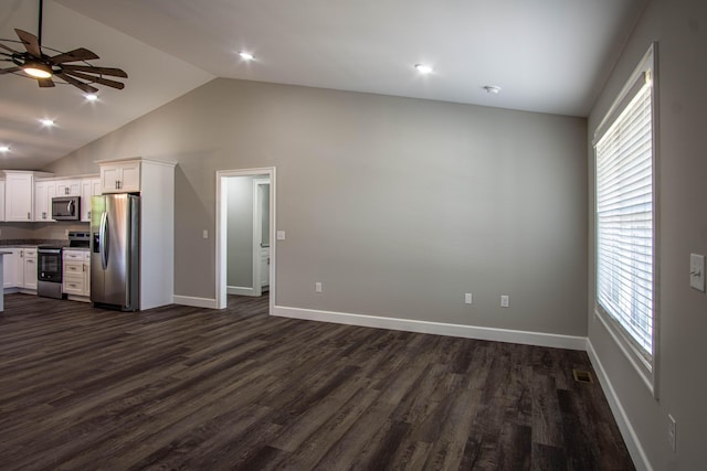 unfurnished living room featuring a ceiling fan, baseboards, a wealth of natural light, and dark wood-type flooring