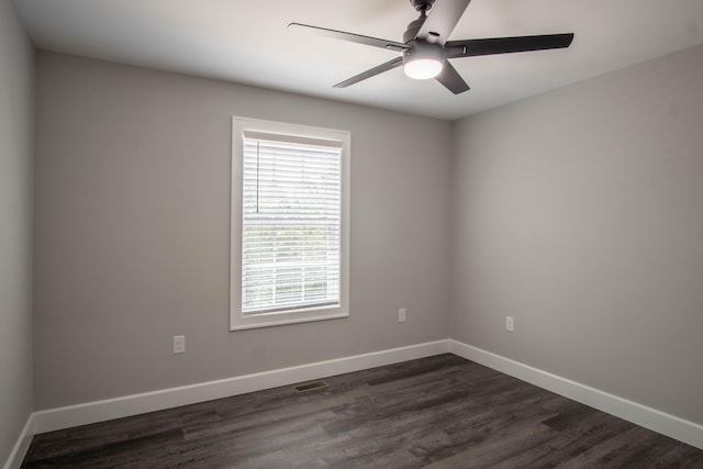 spare room with dark wood-style floors, a ceiling fan, and baseboards