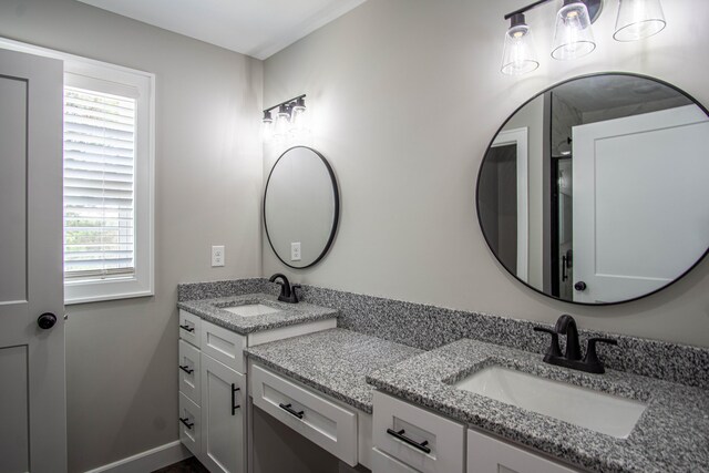 full bath with baseboards, double vanity, and a sink