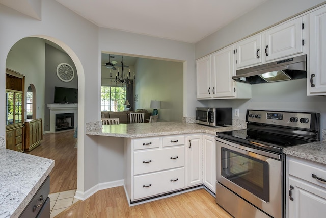 kitchen with stainless steel appliances, under cabinet range hood, light countertops, white cabinets, and healthy amount of natural light