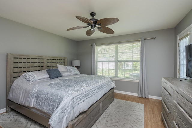 bedroom with multiple windows, baseboards, light wood-style floors, and a ceiling fan