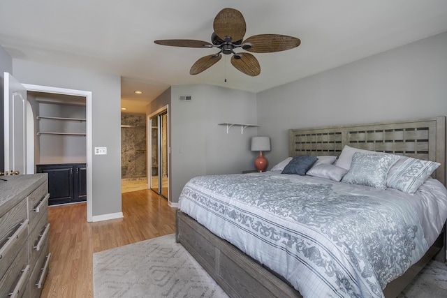 bedroom featuring light wood finished floors, a closet, baseboards, ceiling fan, and ensuite bath