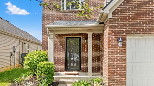 view of exterior entry featuring an attached garage and brick siding