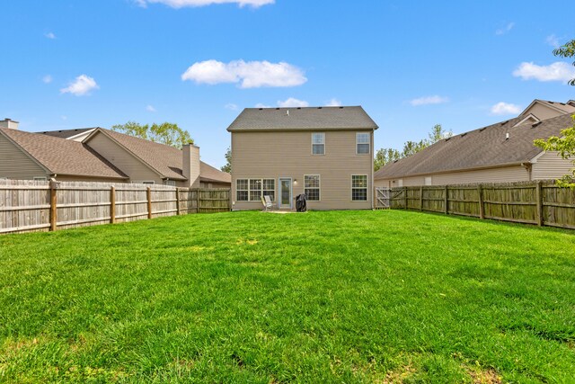 back of property featuring a yard and a fenced backyard