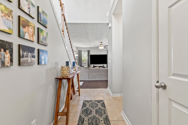 hallway with baseboards, light tile patterned floors, and stairs
