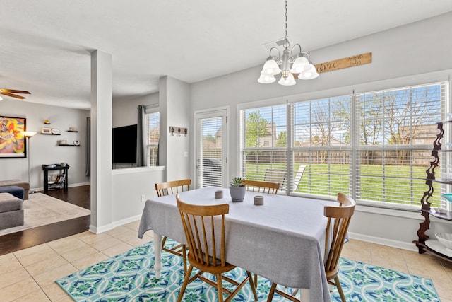 tiled dining space with ceiling fan with notable chandelier and baseboards
