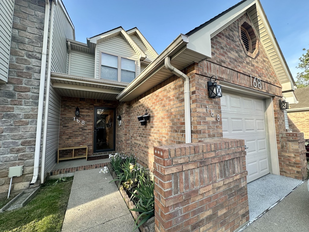 doorway to property featuring brick siding and a garage