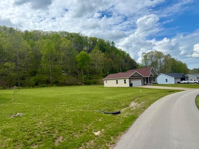 301 Lattern Way, Frenchburg, KY 40322 - exterior space featuring a lawn, aphalt driveway, a forest view, and an attached garage