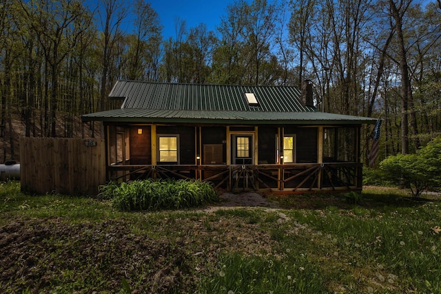 back of property with a chimney, covered porch, and metal roof