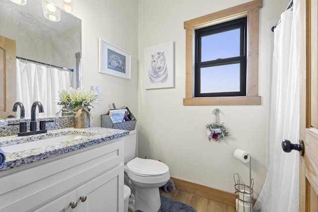 bathroom with vanity, curtained shower, toilet, baseboards, and wood finished floors