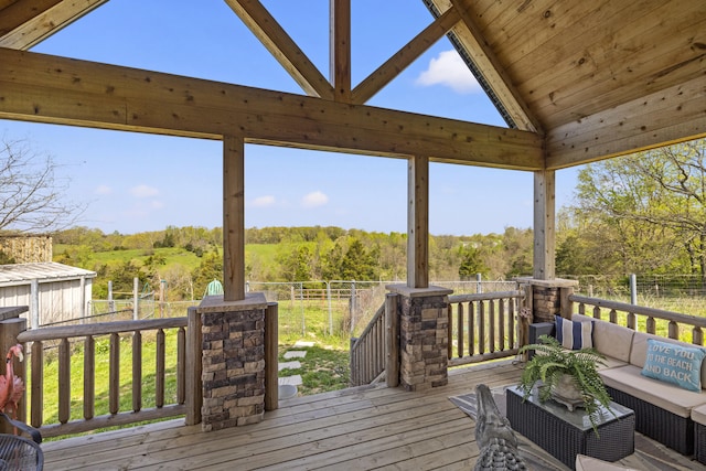 deck featuring an outdoor hangout area, a view of trees, and fence
