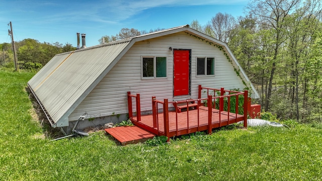 back of property featuring a wooden deck, a yard, and a gambrel roof
