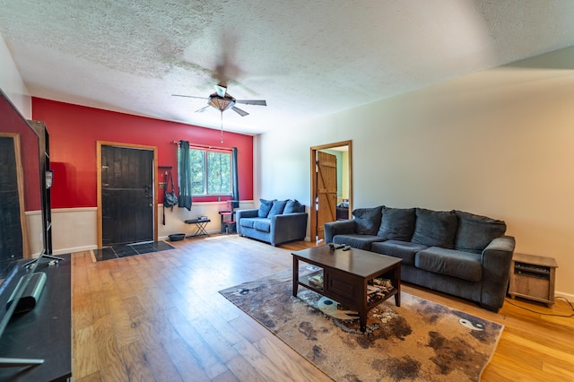 living room featuring a ceiling fan, a textured ceiling, and hardwood / wood-style floors