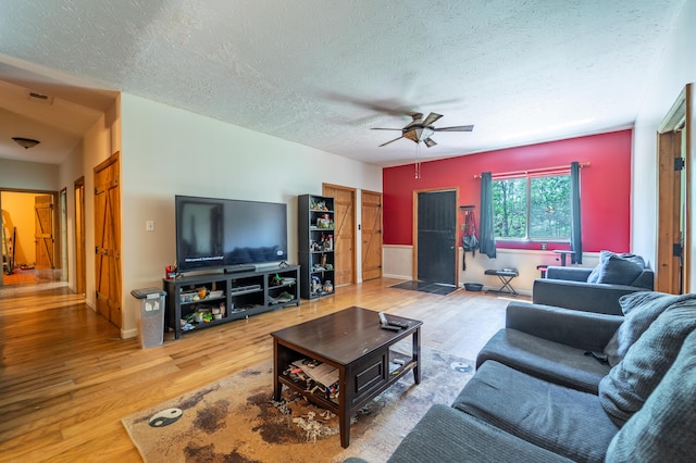 living area with visible vents, wood finished floors, baseboards, a textured ceiling, and a ceiling fan