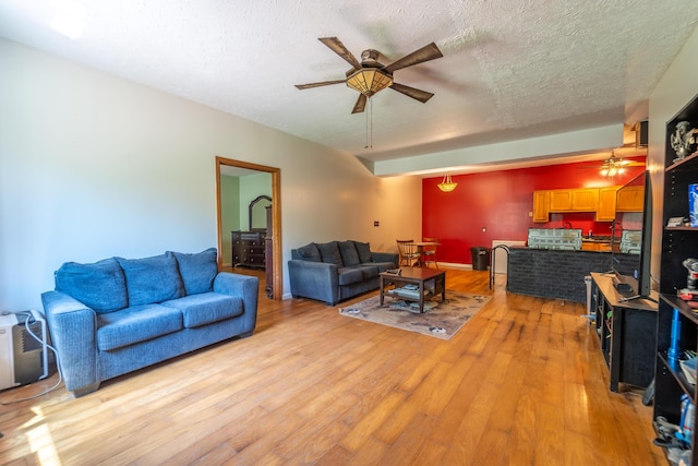 living area featuring a textured ceiling, ceiling fan, and light wood finished floors